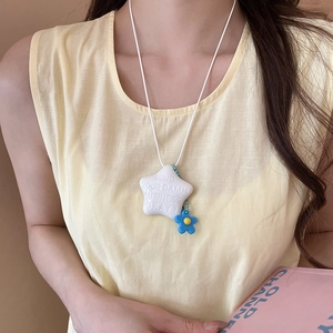 Primo piano della collana a forma di stella con dettaglio floreale e citazione su cordino