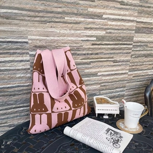 Close-up of pink knit tote bag with rabbit patterns on an outdoor coffee table
