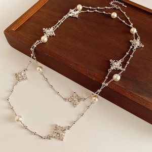Détail d'un collier de perles argenté vintage avec pendentif croix en diamant sur bois