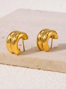 Macro detail of double-layered C-shaped gold-plated crystal stud earrings on stone
