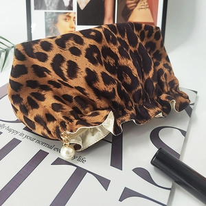 Close-up of leopard print makeup bag with drawstring closure and large pearl charm detail