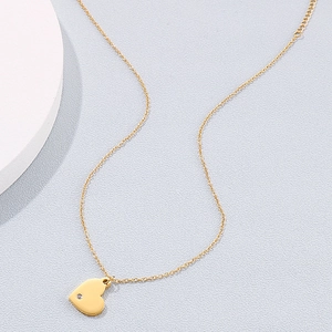 Détail d'un pendentif cœur en or poli avec accent de diamant sur une fine chaîne dorée