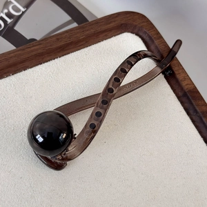 Detailed close-up of a vintage translucent dark brown hair claw clip with a black bead