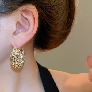 Macro shot of gold spiral nest hoop earrings with pavé diamond pavé setting