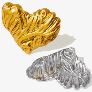 Macro shot of 18k gold and silver heart earrings with irregular lava ripple texture