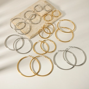 Set of gold and silver stainless steel hoop earrings in various sizes on stone decor