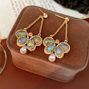 Macro detail of vintage golden butterfly earrings with colorful inlaid crystals
