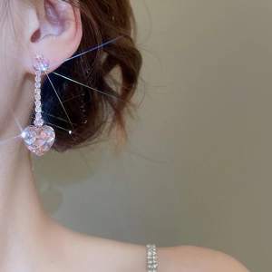 Detail of elegant pink heart crystal earrings with sparkling tassel and floral stud