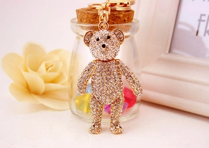 Close-up of golden teddy bear keychain with sparkling crystals in a romantic setting
