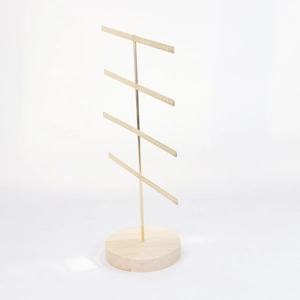 Detail of a four-tier gold metal jewelry stand with a natural wood base and tiny hanging holes