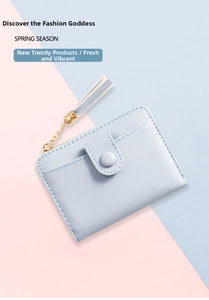 Close-up of light blue small wallet with card slot, snap closure, and tassel detail
