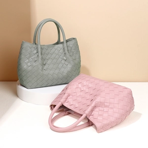 Handwoven mini bucket handbag in sage green and pink colors displayed on a podium