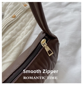 Detailed close-up of dark chocolate quilted leather bag with smooth gold-tone zipper