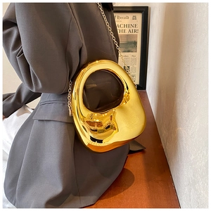 Golden acrylic clutch featuring oval cutout handle and metal chain strap on grey blazer