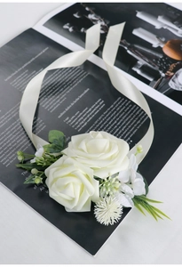 Close-up of elegant ivory artificial rose wrist corsage with delicate silk petals and ribbon