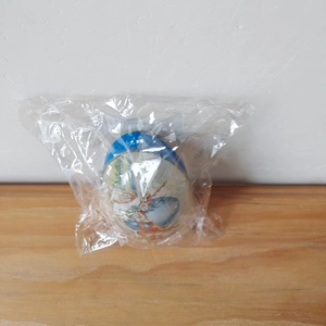 Detail view of blue Easter egg tin box with floral patterns in plastic packaging