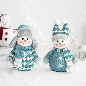 Close-up of knitted snowman plush dolls with blue hats on a snowy holiday background