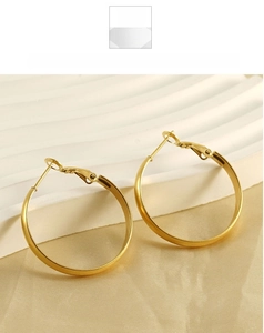 Detail of polished gold hoop earrings featuring secure clasp on a white tray