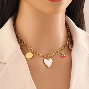 Collana dorata con ciondoli a cuore bianco e ciliegia rossa su una modella
