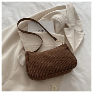 Detail shot of brown woven underarm bag texture with premium leather strap and gold buckle