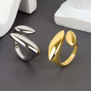 Polished 18K gold and silver oval pea rings shown on an artistic textured surface