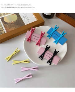 Macro shot of colorful matte X-shaped hair clips in various candy colors on a ceramic plate