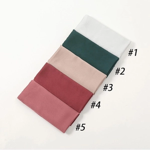 Close-up of folded silk-feel satin hijabs in various elegant solid colors with labels