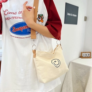Detailed view of off-white canvas crossbody bag with black smiley face print and texture