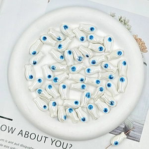 Detailed macro shot of white fish-shaped ceramic beads for DIY jewelry making and crafts