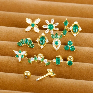 Macro shot of gold stainless steel cartilage studs with green zircon and sparkling crystals