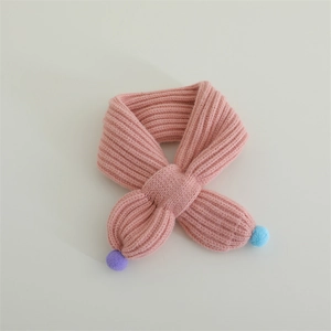 Detail of pink knitted baby scarf featuring soft yarn texture and colorful pompom accents