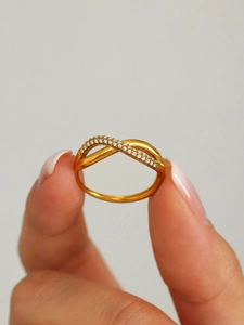 Macro shot of gold-plated infinity cross ring with micro-pave white zircon details