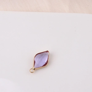 Macro shot of rhombus purple crystal pendant with gold-plated frame for jewelry making