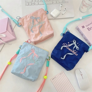 Détail de trois sacs bandoulière en toile colorée avec une élégante broderie de nœud.