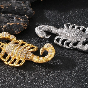 Gros plan de pendentifs scorpion or et argent ornés de strass brillants sur fond noir