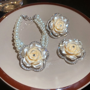 Detail of beaded pearl bracelet and resin rose pendant jewelry set in a ceramic tray
