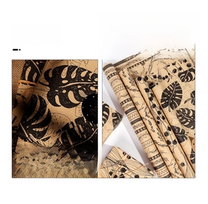 Detail of vintage kraft paper gift wrap with black botanical prints and monstera leaf pattern