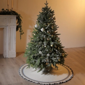 Knitted Christmas tree skirt with Fair Isle patterns and fringe in a cozy home setting
