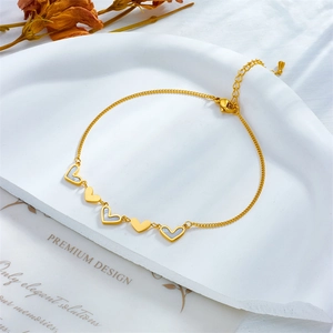 Gold chain anklet featuring five heart charms with white shell inlay on a white stone tray