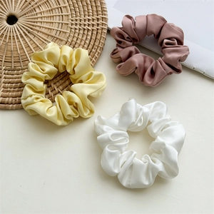 Detail of satin scrunchies set in yellow, pink and white with smooth silk texture