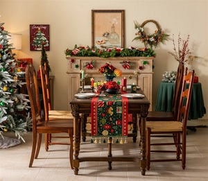 Detail of green Christmas table runner with festive jacquard patterns and red tassel edges