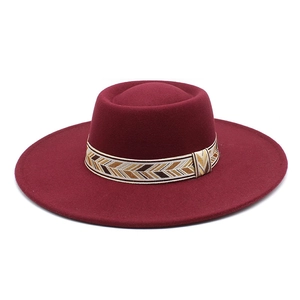 Detail of dark wine red wool fedora with a patterned geometric hat band on white background