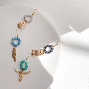 Detail of bohemian drop earrings with natural turquoise stones and gold bull head charms