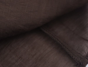 Vue macro d'un textile marron foncé montrant la texture du tissage et les coutures