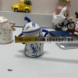 Close-up of a white ceramic storage jar with blue floral patterns and measurement tape