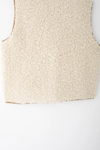 Détail de l'arrière d'un gilet en peau lainée beige avec bordure contrastée brune