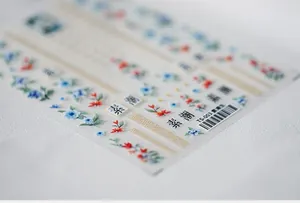 Macro shot of 5D floral nail art stickers with delicate blue flowers and gold accents