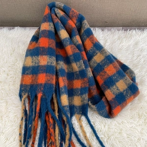 Cozy winter plaid scarf featuring blue and orange check pattern and soft fringe trim.