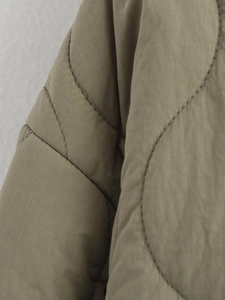 Detailed close-up of olive green quilted jacket featuring classic onion pattern stitching