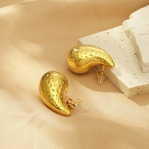 Detail of 18K gold stainless steel teardrop earrings with hammered texture on silk and stone